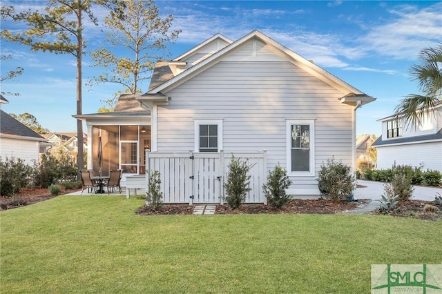 back of property featuring a lawn, a sunroom, and a patio