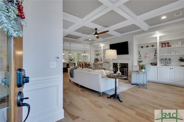 living room featuring beamed ceiling, ceiling fan, light hardwood / wood-style floors, and coffered ceiling