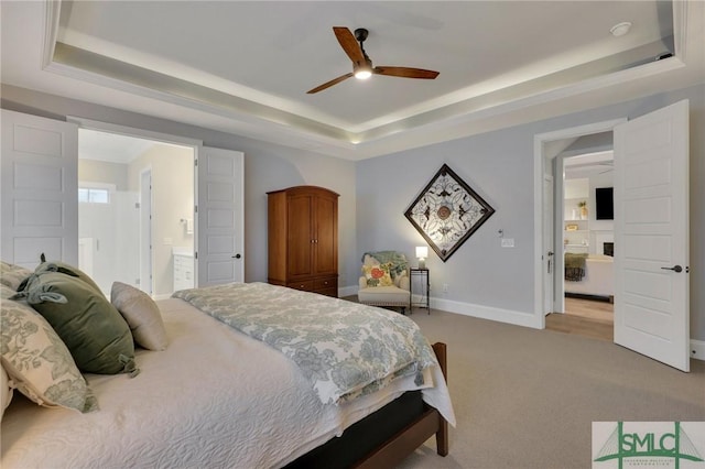 carpeted bedroom with connected bathroom, a tray ceiling, and ceiling fan