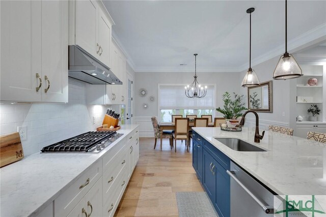 kitchen featuring stainless steel appliances, sink, blue cabinetry, pendant lighting, and white cabinetry