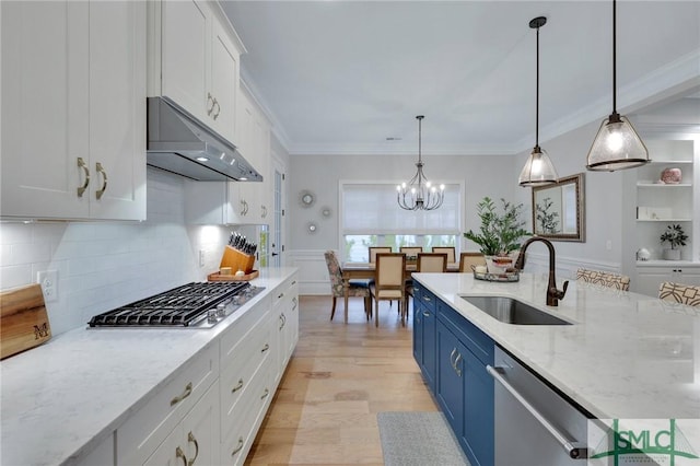 kitchen with appliances with stainless steel finishes, sink, white cabinetry, blue cabinetry, and pendant lighting