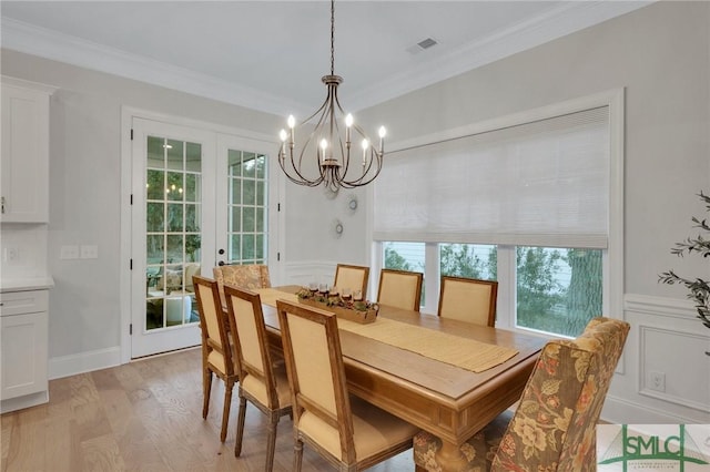 dining space with a notable chandelier, ornamental molding, and light wood-type flooring