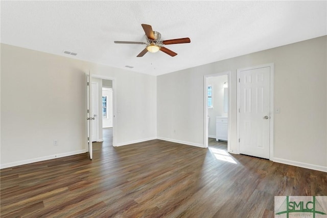 spare room with a textured ceiling, ceiling fan, dark wood-type flooring, and a wealth of natural light