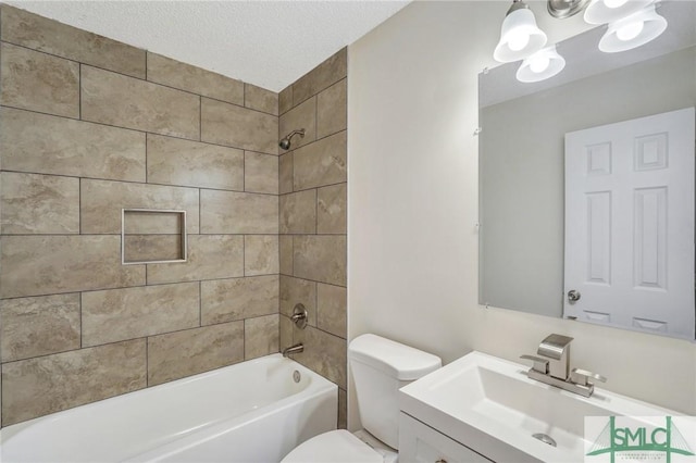 full bathroom featuring toilet, vanity, a textured ceiling, and tiled shower / bath