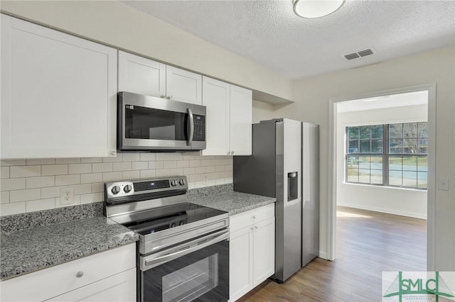 kitchen with white cabinets, stainless steel appliances, and light stone counters