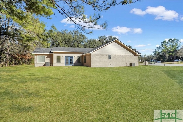 rear view of property with a yard and central AC unit