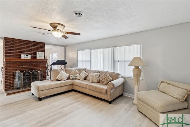 108 Dawson Ln, Ludowici, GA 31316 - living room featuring a brick fireplace, a textured ceiling, light hardwood / wood-style flooring, and ceiling fan