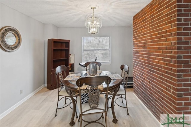 108 Dawson Ln, Ludowici, GA 31316 - dining room featuring a textured ceiling, light wood-type flooring, a notable chandelier, and brick wall