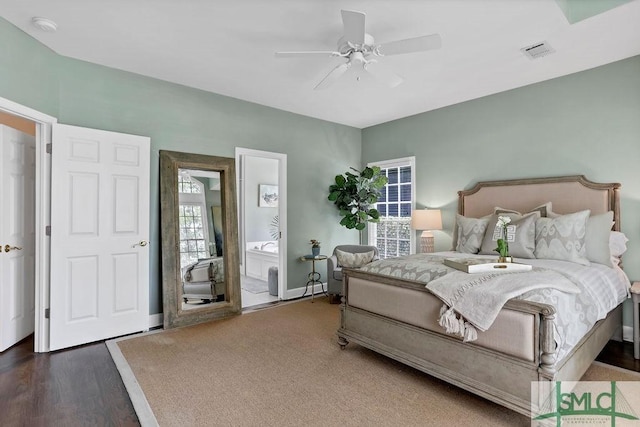 bedroom featuring ensuite bathroom, ceiling fan, dark hardwood / wood-style flooring, and multiple windows