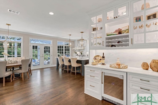 bar featuring french doors, wine cooler, crown molding, white cabinetry, and hanging light fixtures