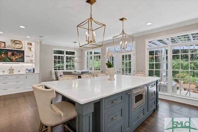 kitchen featuring a center island, french doors, crown molding, pendant lighting, and white cabinets