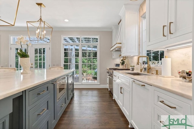 kitchen with sink, white cabinets, stainless steel stove, and decorative light fixtures