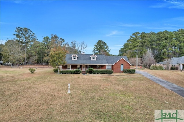 cape cod home featuring covered porch and a front yard