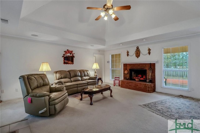 living room featuring ceiling fan, a raised ceiling, light colored carpet, and a fireplace