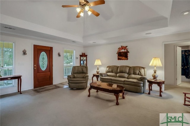 living room with carpet, a raised ceiling, plenty of natural light, and ceiling fan