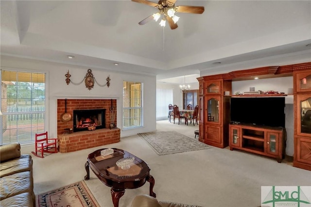 living room featuring carpet flooring, ceiling fan with notable chandelier, a raised ceiling, and a fireplace