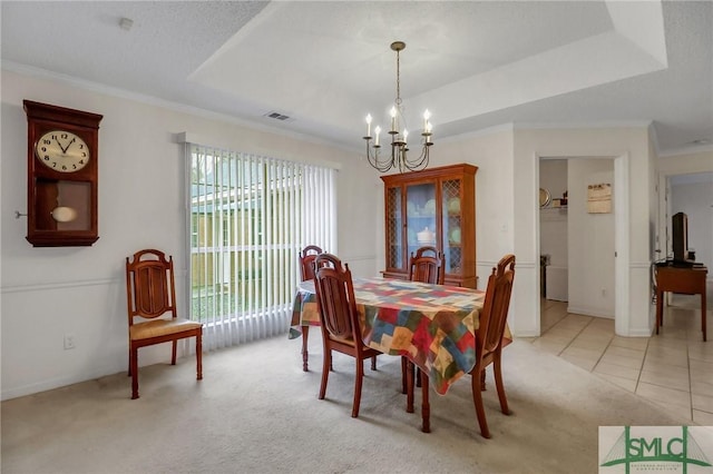 dining room with light tile patterned flooring, a raised ceiling, ornamental molding, and an inviting chandelier