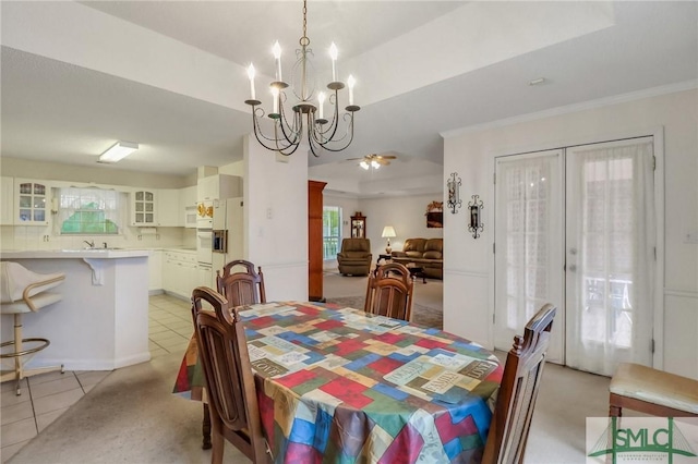 tiled dining area with ceiling fan with notable chandelier, a healthy amount of sunlight, crown molding, and french doors