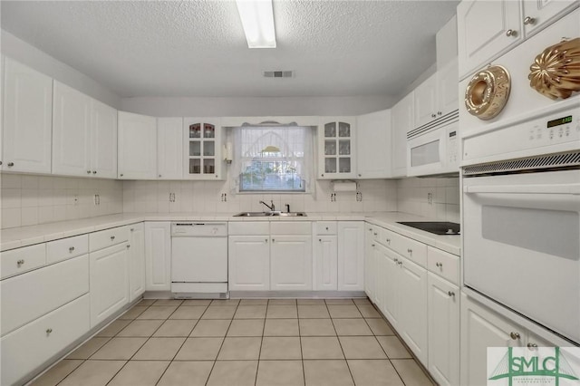 kitchen with white cabinetry, sink, light tile patterned flooring, and white appliances