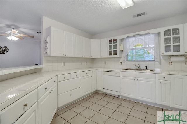 kitchen with dishwasher, sink, light tile patterned floors, tasteful backsplash, and white cabinetry