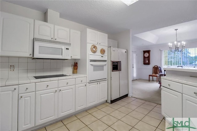 kitchen featuring pendant lighting, white appliances, decorative backsplash, white cabinetry, and a chandelier