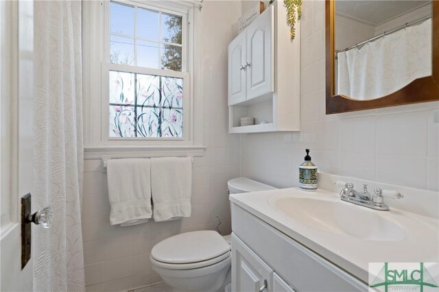 bathroom with vanity, toilet, and tile walls