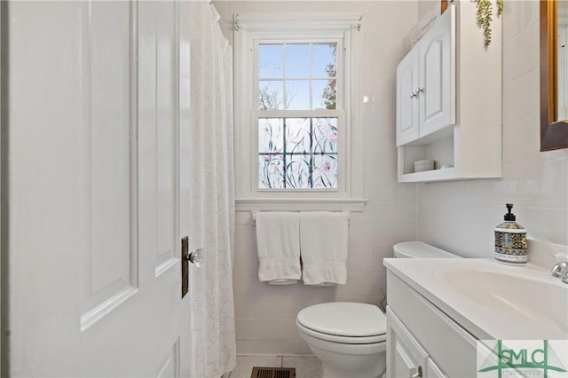 bathroom with tile patterned floors, vanity, toilet, and tile walls