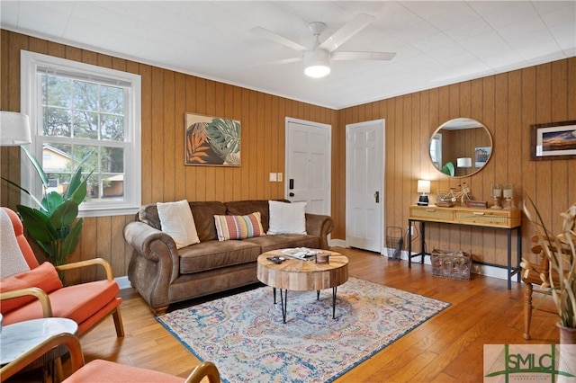 living room with ceiling fan, hardwood / wood-style floors, and wood walls