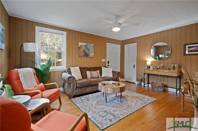 living room featuring ceiling fan, wood-type flooring, and wood walls