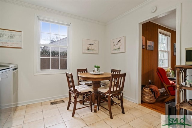 dining area with crown molding, plenty of natural light, light tile patterned floors, and wood walls