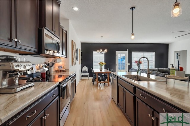 kitchen with a textured ceiling, stainless steel appliances, dark brown cabinetry, sink, and decorative light fixtures