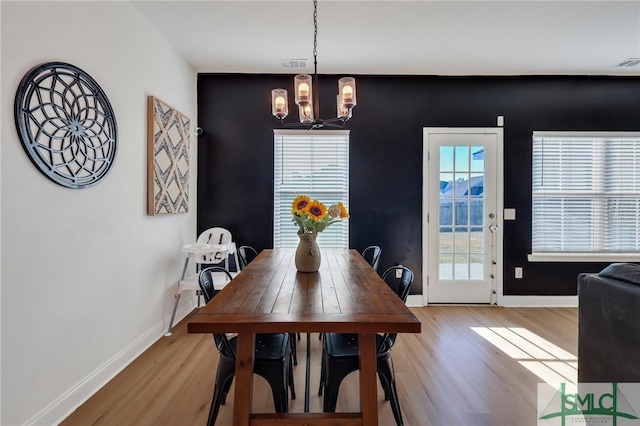 dining room featuring plenty of natural light, light wood-type flooring, and an inviting chandelier