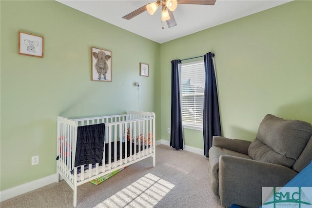 carpeted bedroom with ceiling fan and a crib