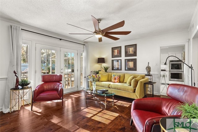 living room featuring ceiling fan, french doors, a textured ceiling, hardwood / wood-style flooring, and ornamental molding