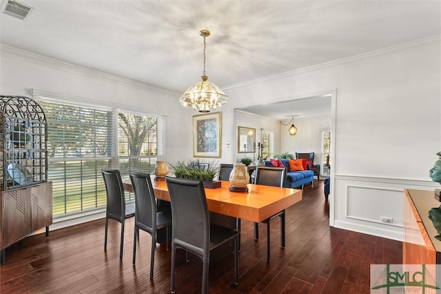 dining room with ornamental molding, dark wood-type flooring, and an inviting chandelier