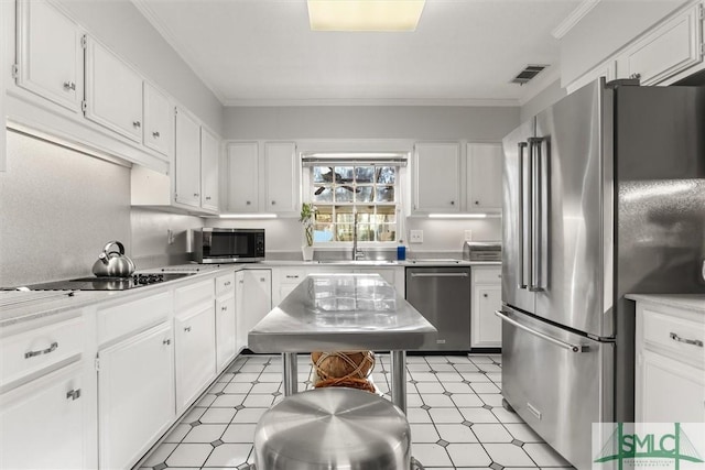 kitchen featuring a center island, white cabinets, sink, crown molding, and appliances with stainless steel finishes