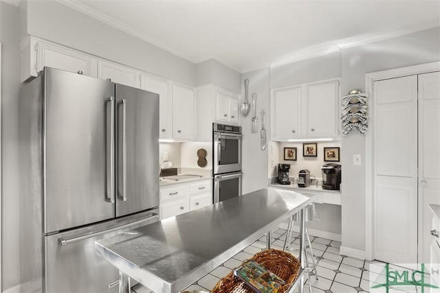 kitchen with white cabinets, appliances with stainless steel finishes, and crown molding