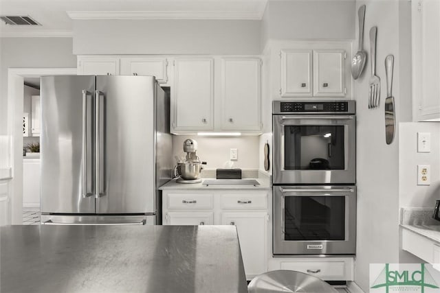 kitchen with white cabinets, stainless steel appliances, and ornamental molding