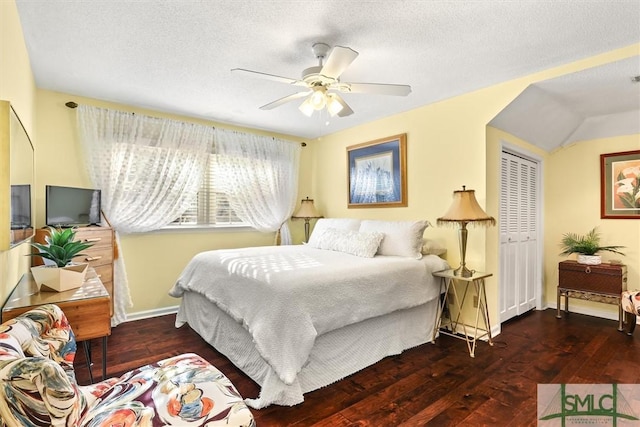 bedroom with a textured ceiling, ceiling fan, dark wood-type flooring, and a closet