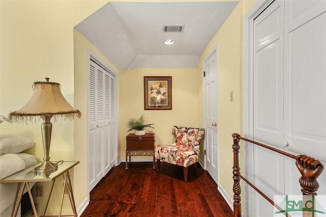 hall with a textured ceiling, lofted ceiling, and dark wood-type flooring