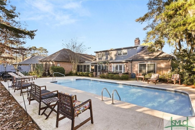 view of pool with a sunroom and a patio area