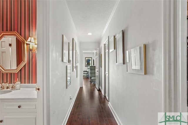 hallway with sink, dark hardwood / wood-style flooring, a textured ceiling, and ornamental molding