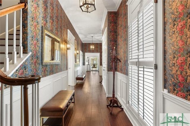 corridor with dark hardwood / wood-style flooring, ornamental molding, and a notable chandelier