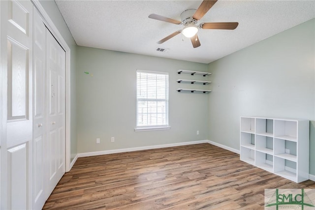 unfurnished bedroom featuring a textured ceiling, hardwood / wood-style flooring, a closet, and ceiling fan