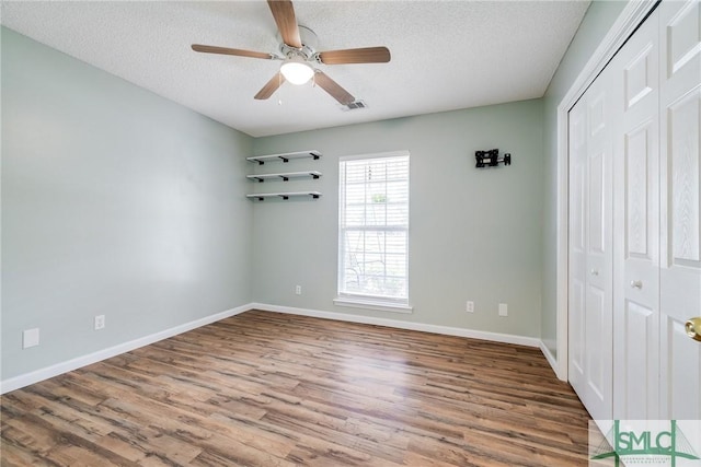 unfurnished bedroom featuring a textured ceiling, a closet, ceiling fan, and hardwood / wood-style flooring