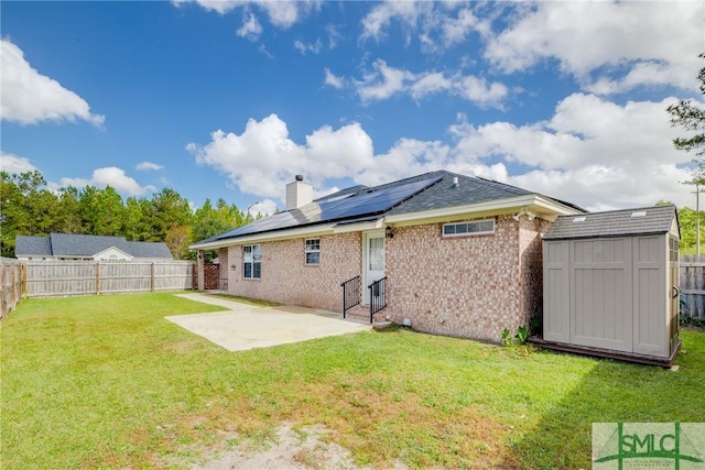 back of property featuring solar panels, a shed, a yard, and a patio