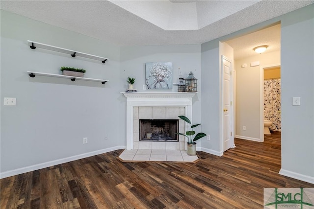 unfurnished living room featuring a tile fireplace, a textured ceiling, and dark hardwood / wood-style floors