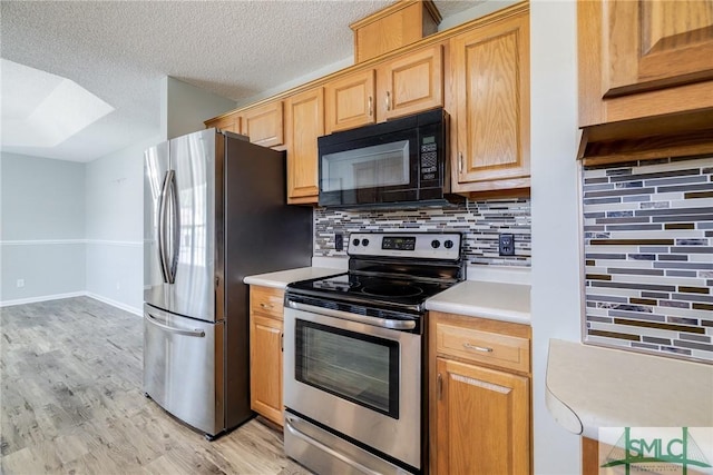 kitchen featuring tasteful backsplash, light hardwood / wood-style flooring, a textured ceiling, and appliances with stainless steel finishes