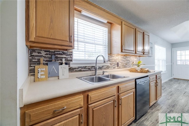 kitchen featuring dishwasher, backsplash, sink, light wood-type flooring, and a textured ceiling