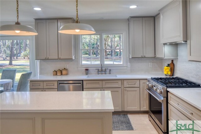 kitchen with appliances with stainless steel finishes, tasteful backsplash, decorative light fixtures, and sink